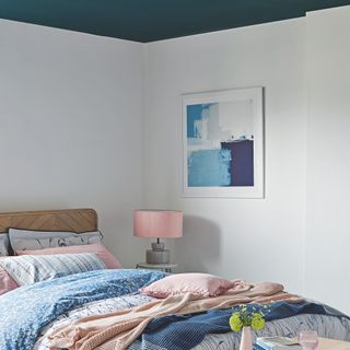 bedroom with white walls and teal ceiling bed with wooden headboard and pink blue and white bedding