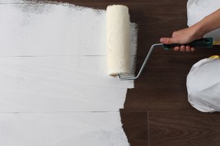 Painting floorboards with a paint roller