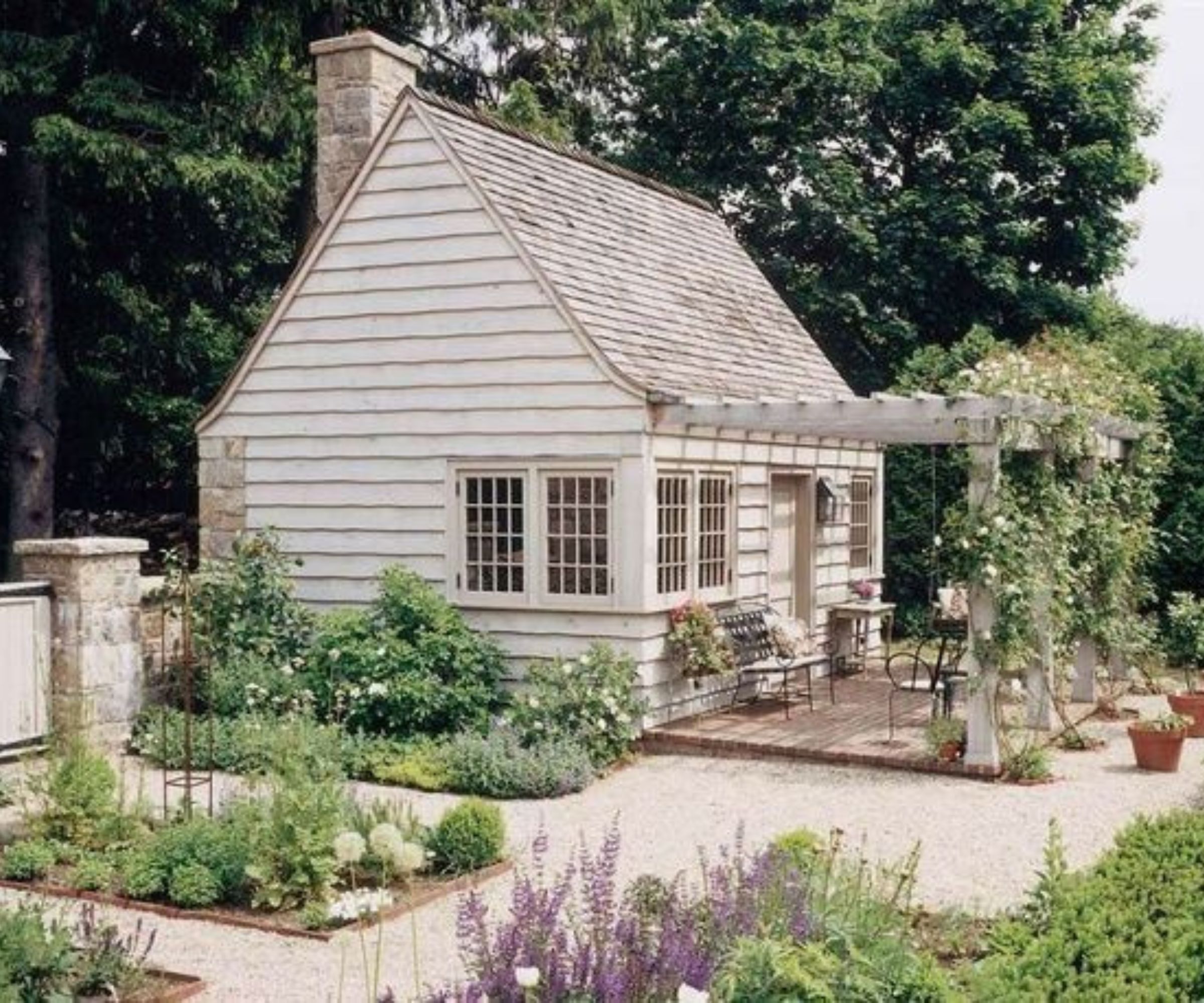 rustic shiplapped garden room with a pergola and shingle patio with kitchen garden flower beds and a patio set