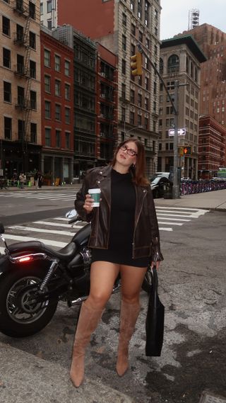 Rae wears a brown leather jacket, black minidress, tan suede knee-high boots