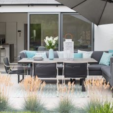 paved area with grey outdoor sofa and umbrella