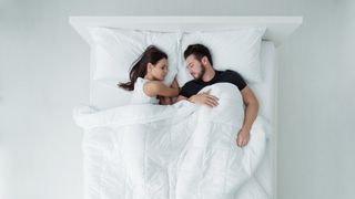How long does a mattress last: a man and woman sleep on a queen-size mattress dressed with white sheets