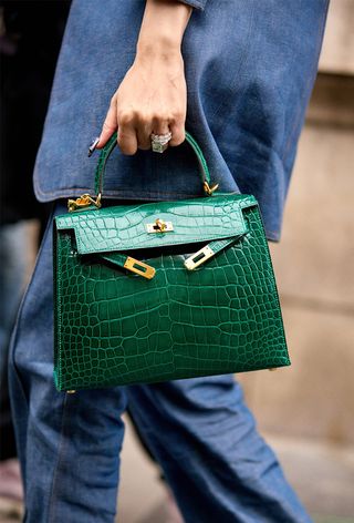 a street style photo of a woman carrying an Hermés bag in a story about how to buy an hermés bag