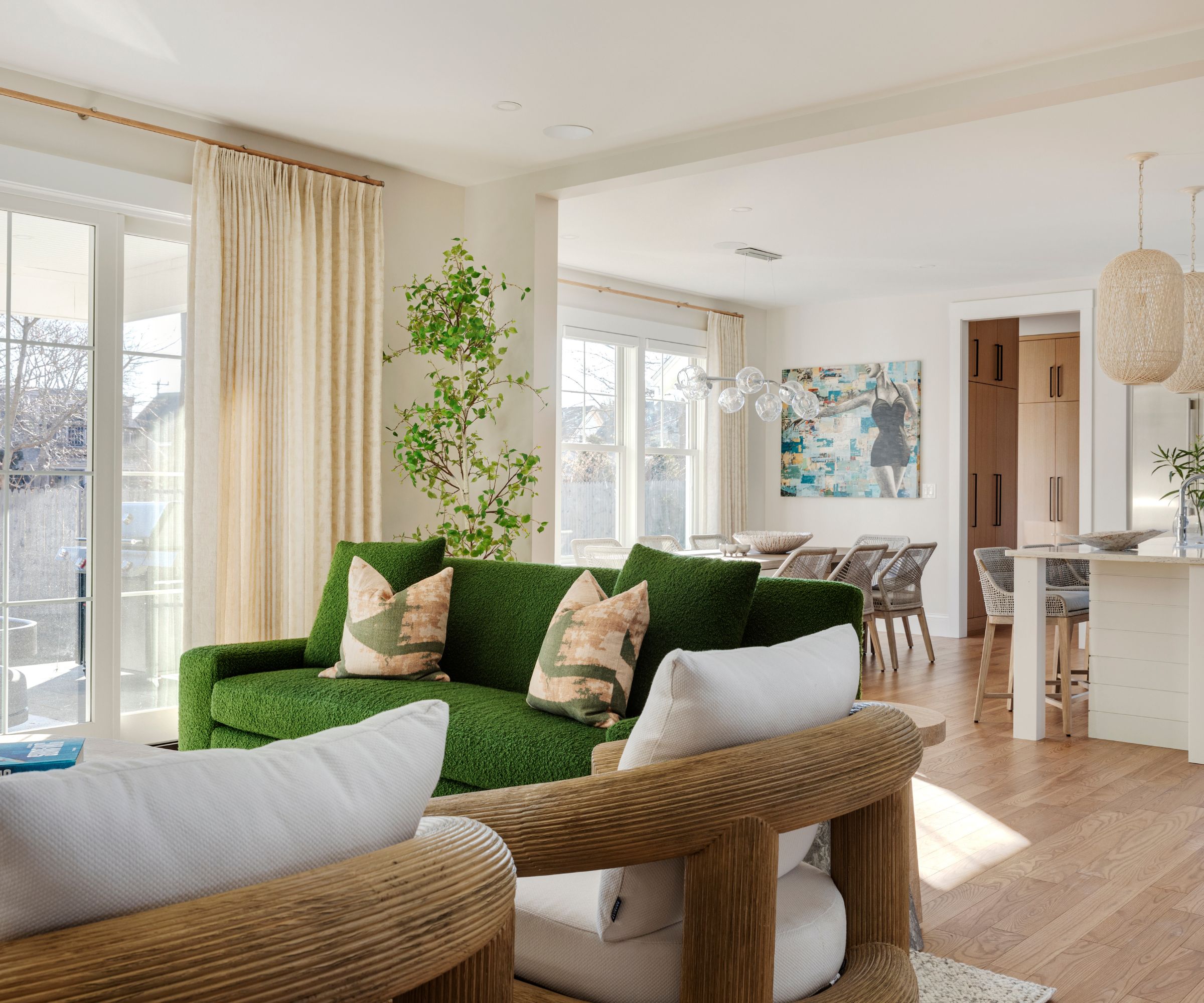 Living room with wood floor, white walls, potted plant, cream curtains and bright green sofa