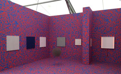 Red and blue patterned wall and floor with square art on the walls