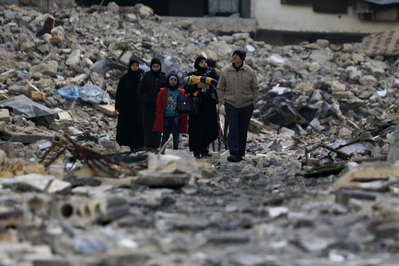 Syrian walk the rubble of their former neighborhood in eastern Alyppo.