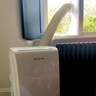 The Russell Hobbs RHPAC11001 Portable Air Conditioner being vented out of a window with the exhaust hose