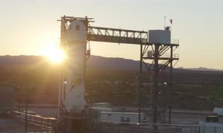 The sun rises over Blue Origin's New Shepard spacecraft and booster at the company's West Texas test site.