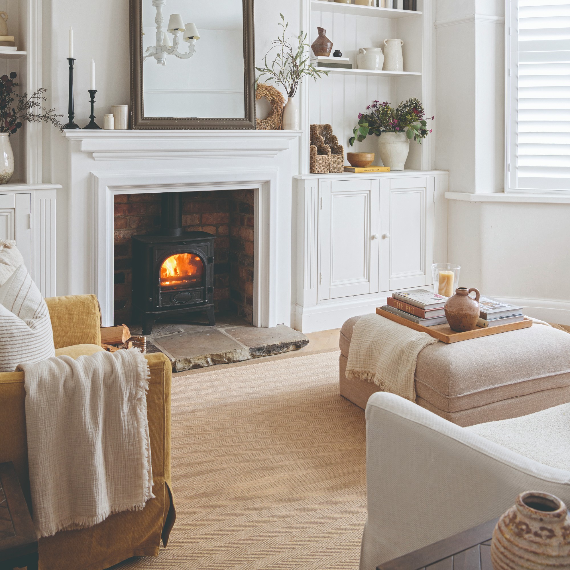 A white living room with a beige herringbone jute rug and a mustard yellow armchair