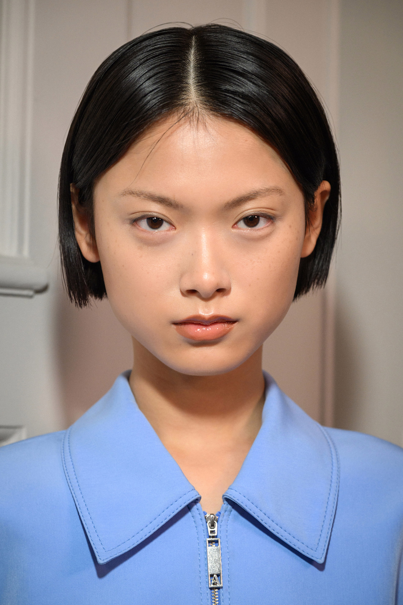 A model showing off a middle-parted, straight bixie cut.