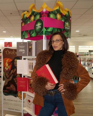 A photo of Bella Hadid posing at Ulta in a brown Penny Lane coat from Anna Sui.