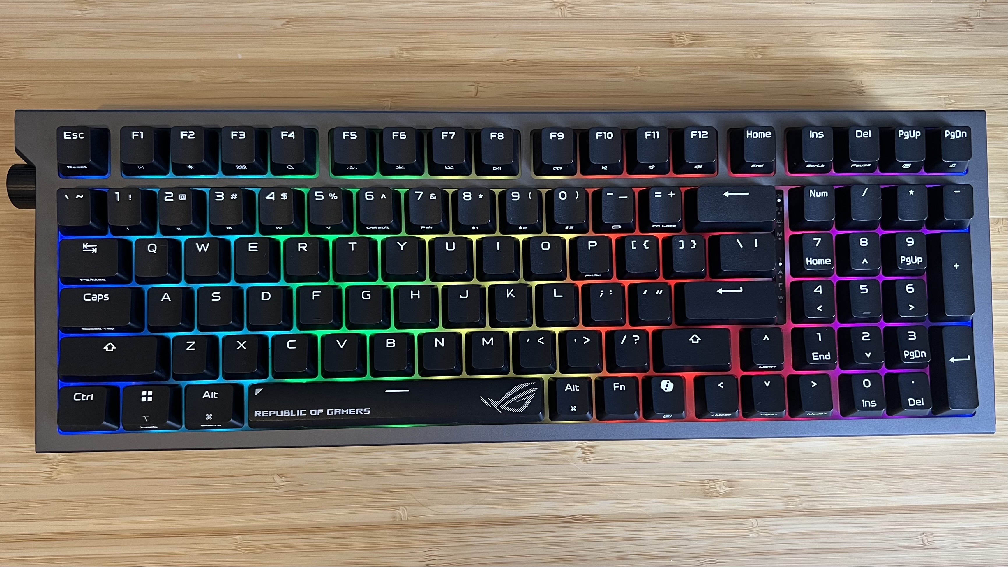 Asus ROG Strix Morph 96 Wireless gaming keyboard on a wooden desk with RGB lighting on