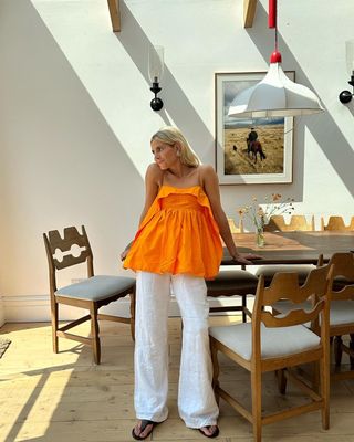 @lucywilliams02 wearing white linen trousers with an orange top