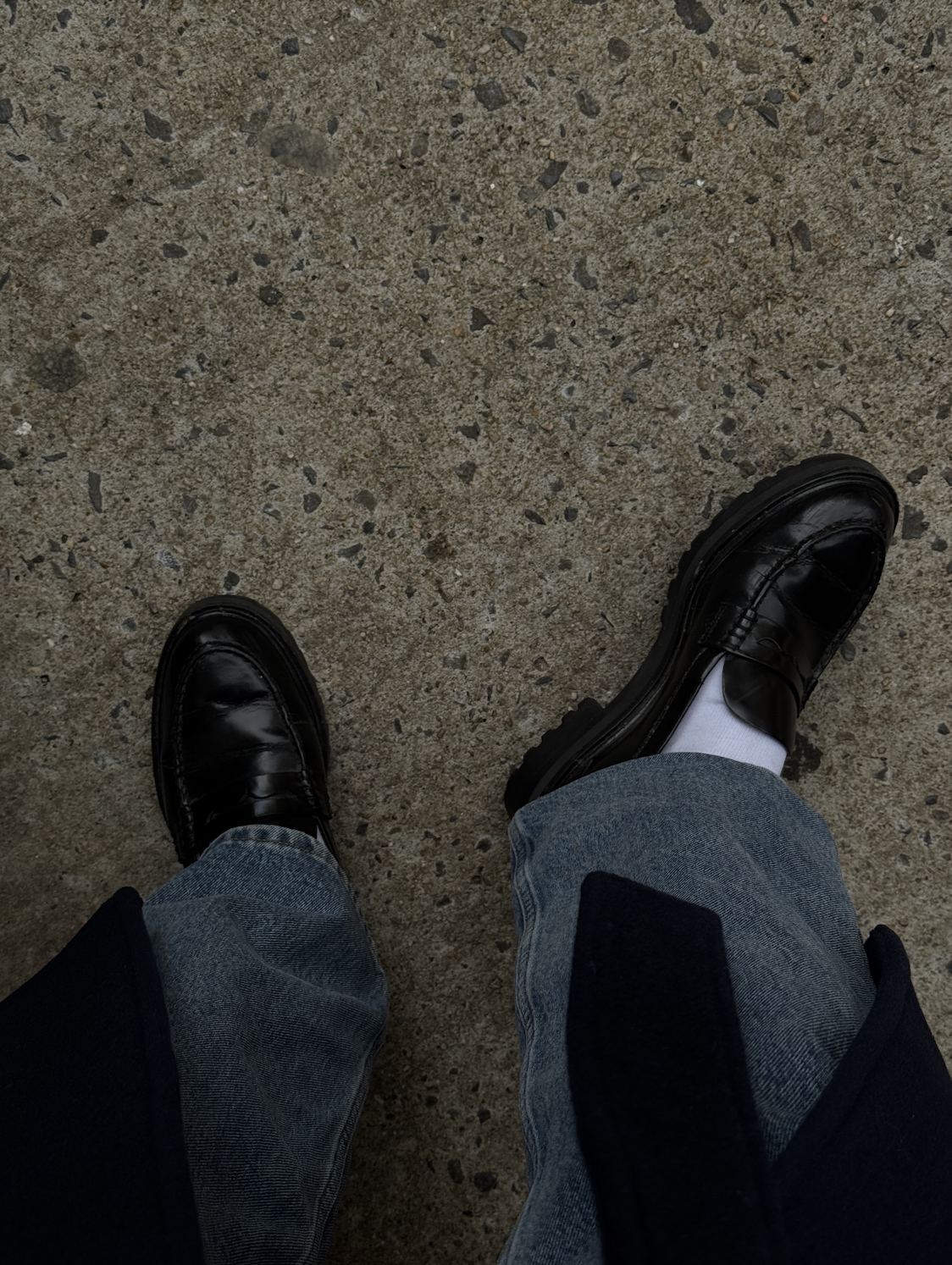 black loafers, white socks, and jeans on sidewalk