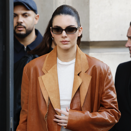 Kendall Jenner wears white top, brown leather double blazer, brown suede Herm&egrave;s bag, black trousers, black boots, black sunglasses, outside Schiaparelli, during Haute Couture Spring-Summer 2025 as part of Paris Fashion Week on January 27, 2025 in Paris, France