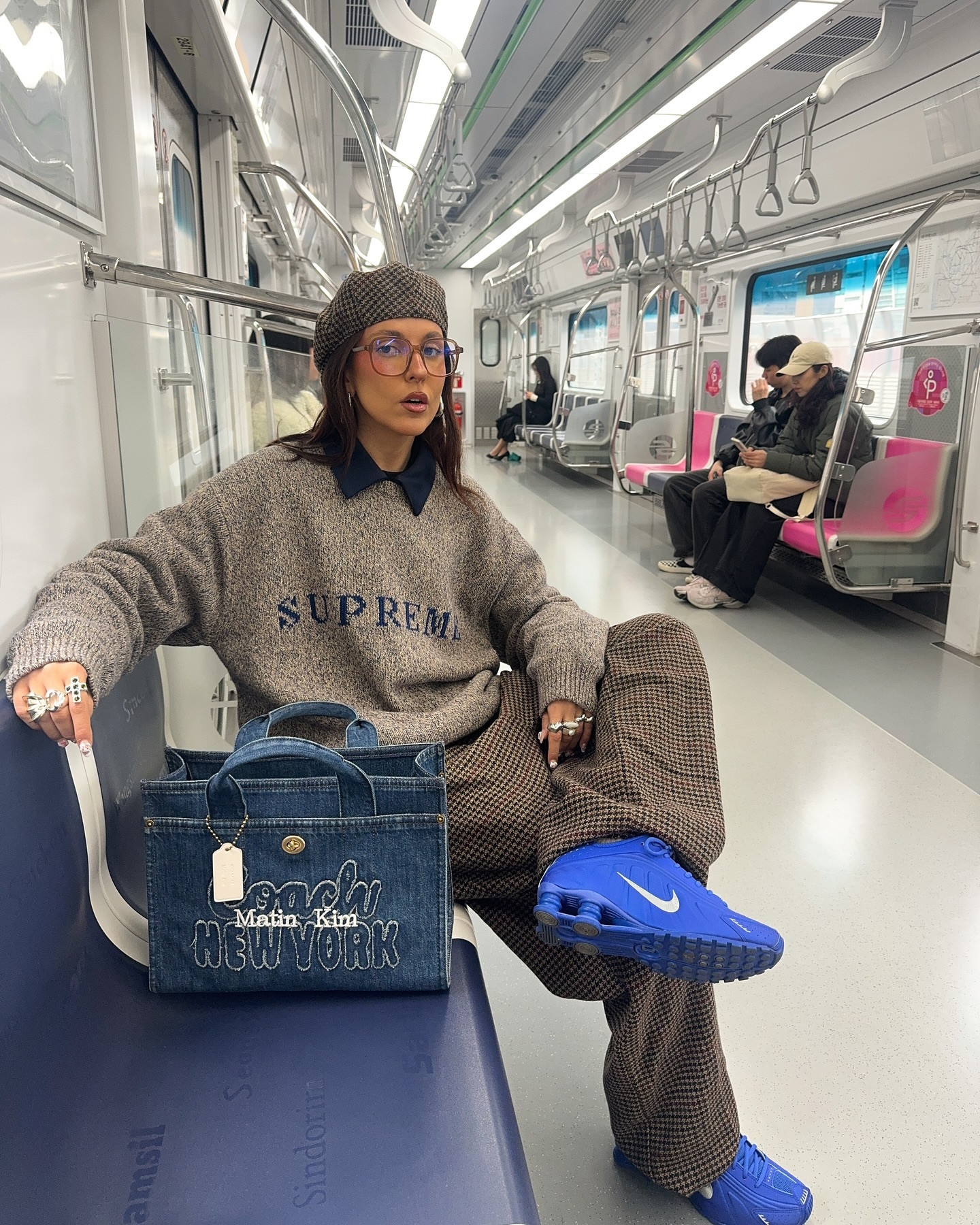 Sofia wears a sweater, trousers, and Nike Shox with a tote bag.