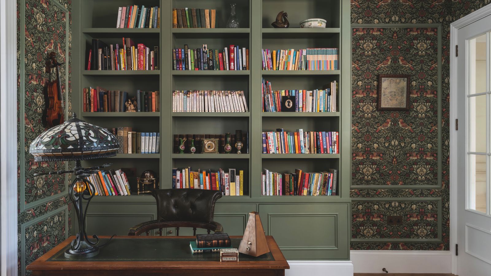 A dark green built-in shelving in a home office. 