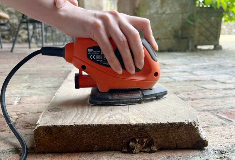 A woman sanding a piece of scaffold board 