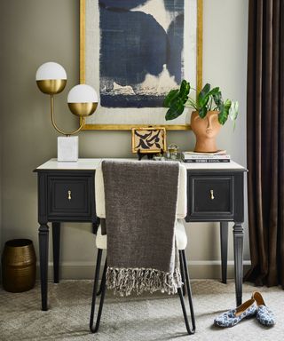 bedroom with dressing table / desk area with globe table lamp, plant, books, throw over chair, slippers, artwork, brown curtains to the right