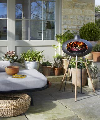 A barbecue on tripod legs illustrates outdoor kitchen designs in a paved patio scheme.
