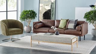 A living room with a brown leather sofa and green accent chair for sustainable furniture brands.