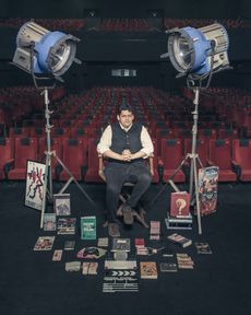 Man sitting in a theatre with many books on the floor