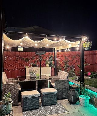 Night garden with pergola lit by festoon lighting, and outdoor heater.