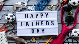 Photo of a sign that reads Happy Father's Day surrounded by ties, sunglasses, tools, and more