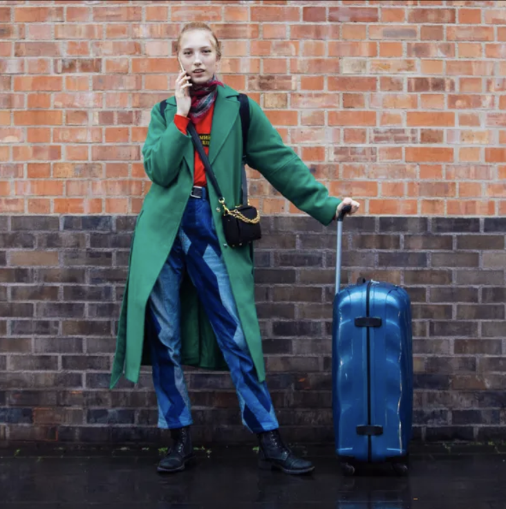 photo of woman wearing a green coat, blue pants, and a red top