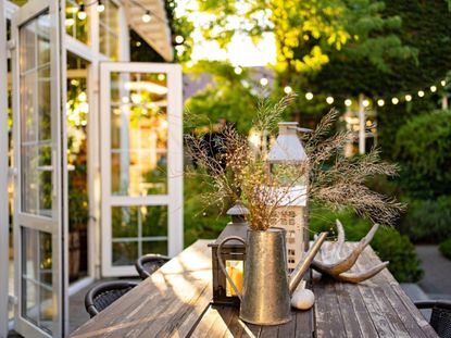 A beautiful outdoor table next to a greenhouse with string lights in the background