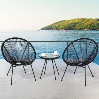 two woven black egg chairs and matching table on a sea-view terrace