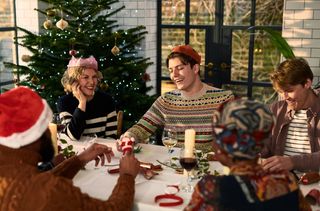 A happy family wearing Christmas cracker crowns, playing Christmas dinner games.
