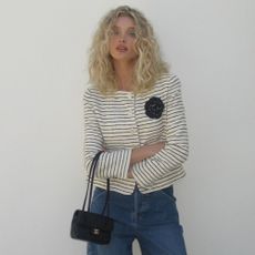 Elsa Hosk poses for a photo wearing a striped cropped jacket with wide-leg jeans and white pointed-toe heels.