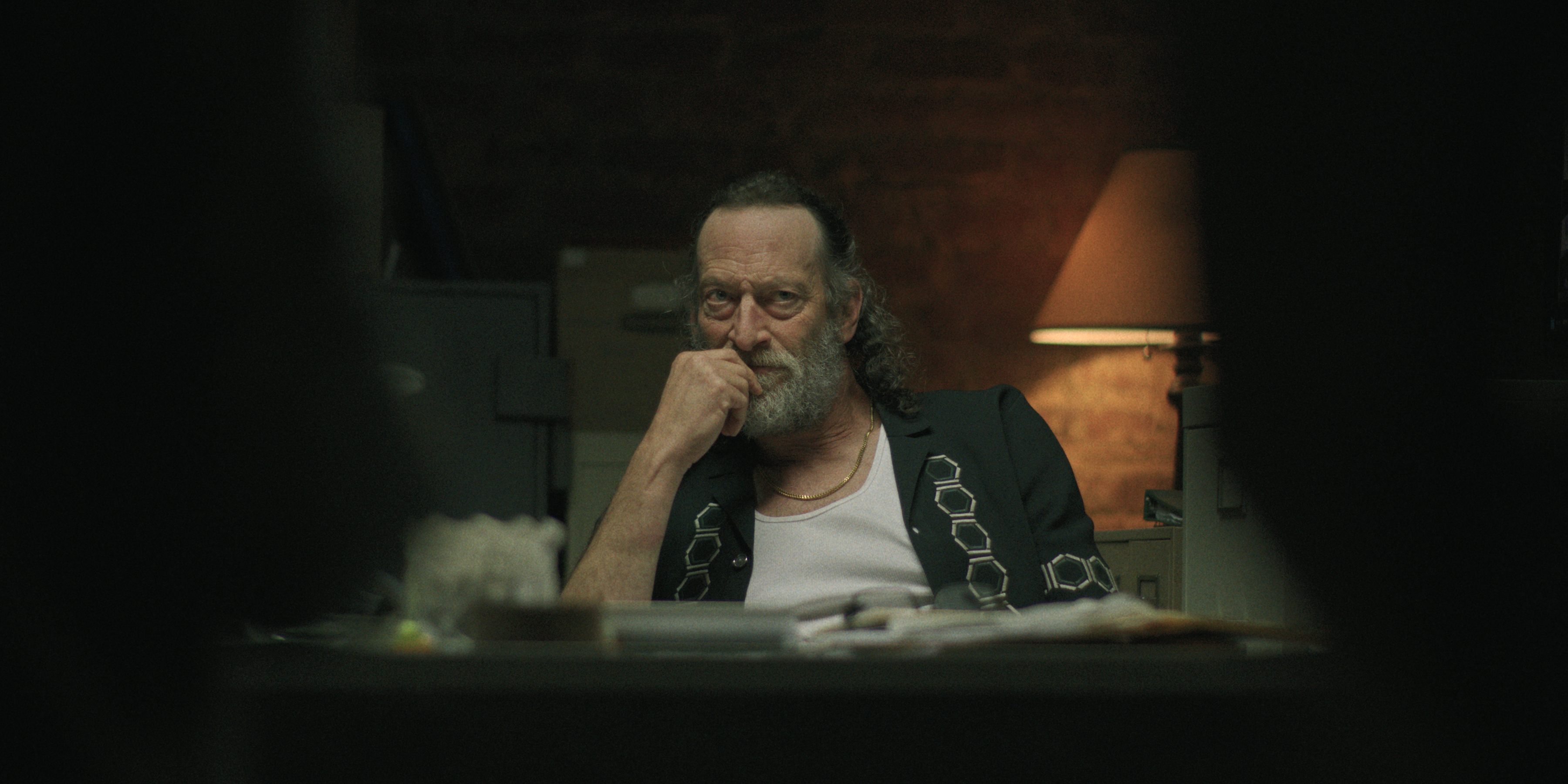 troy kotsur as a crime boss at a table looking menacing in black rabbit