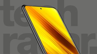 Bästa billiga mobil: En Xiaomi Poco X3 NFC med en ljusgul bakgrundsbild visas mot en grå bakgrund med texten "TechRadar" i stora mörkgrå bokstäver.