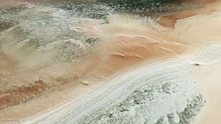 A satellite view of a landscape with swirling brown and green dunes