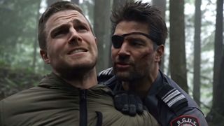 Unmasked Slade Wilson holding Oliver's arm behind his back painfully in Arrow