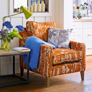 orange chair with wooden flooring and table lamp