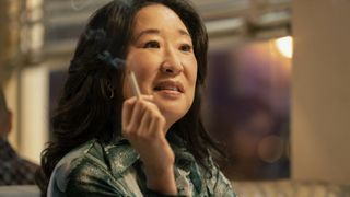 Sandra Oh in a green top holding a cigarette as Sofia Mori in The Sympathizer.