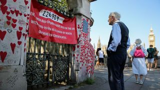 An older man stands in front of the National Covid Memorial Wall in London in the UK.