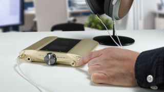 iFi iDSD Valkyrie in gold, on a beige desk