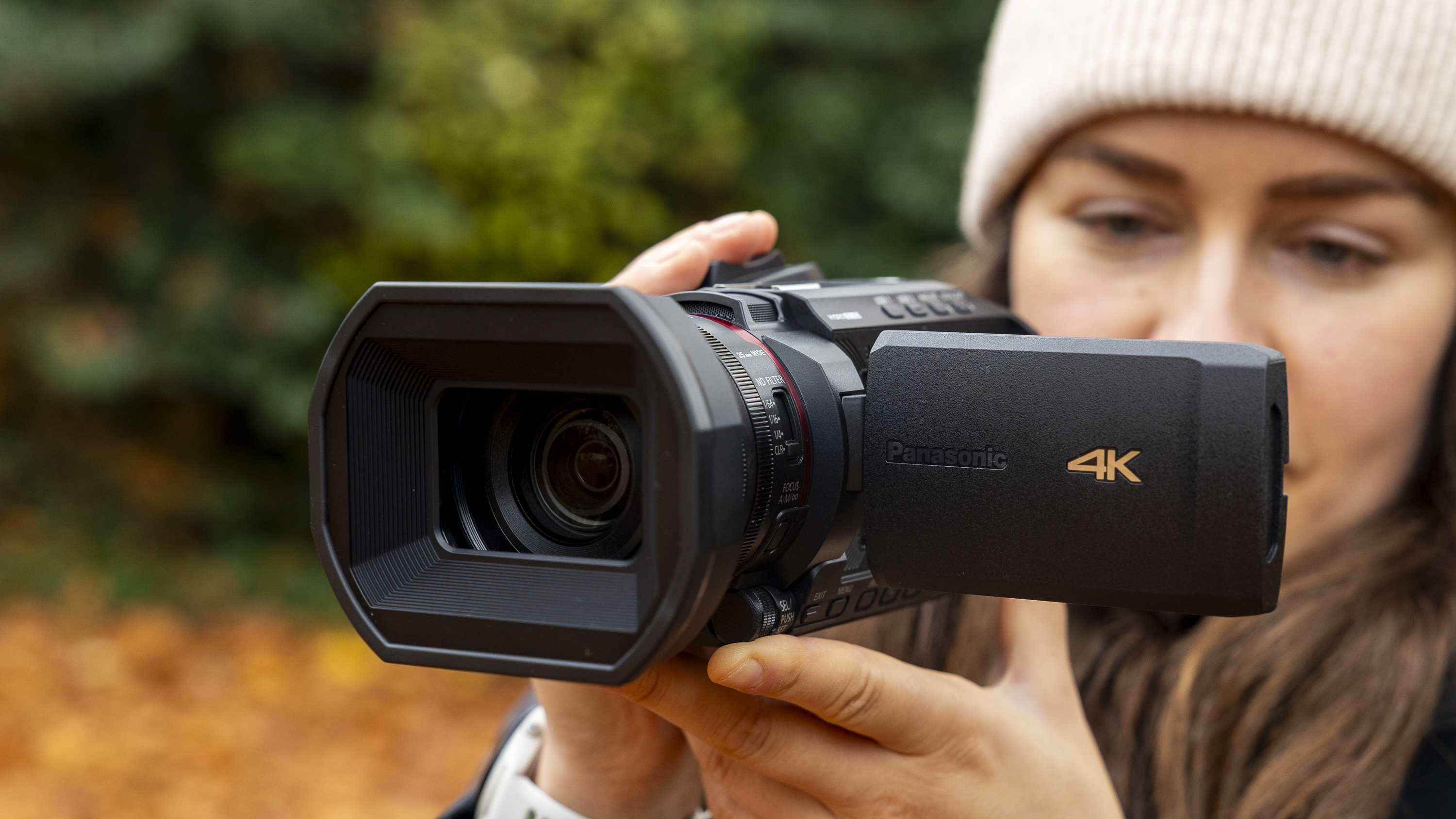 The Panasonic HC-X1200 camcorder held by a female photographer against an orange autumnal backdrop