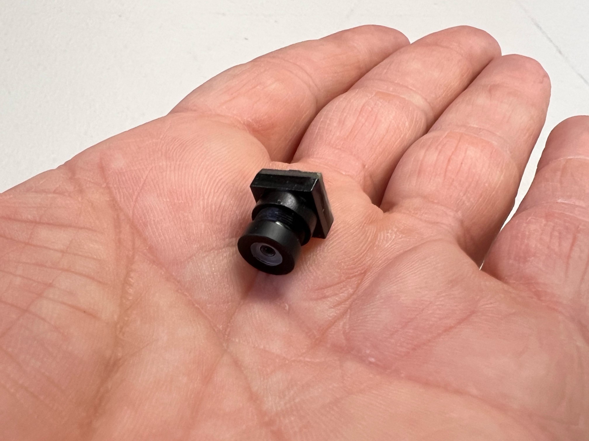 Tiny camera in a hand that is used for the driver's eye view perspective.