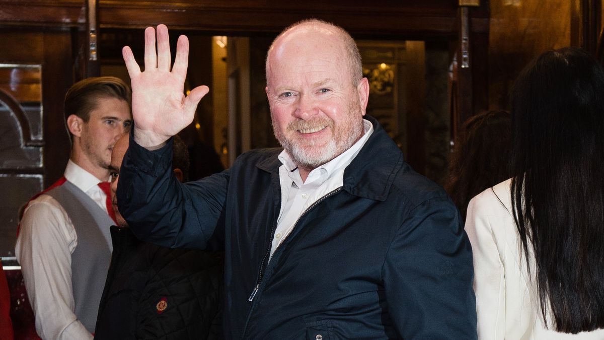 Steve McFadden attends the opening night of &quot;Cinderella&quot; at London Palladium wearing a black jacket over a white shirt and smiling and waving to the camera 