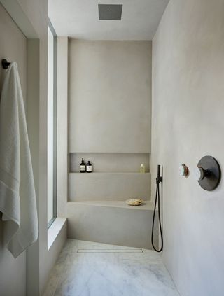 a tadelakt shower with a recess in the wall and built-in seat