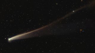 A photo of a gold-colored comet with a long rippling tail in the night sky