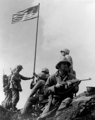 Photo of the first U.S. flag raising on Iwo Jima, taken by Staff Sergeant Louis R. Lowery, USMC, staff photographer for Leatherneck magazine.