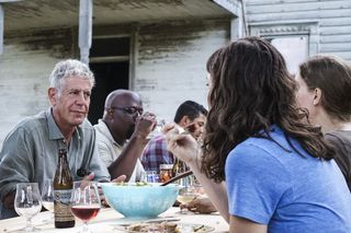 Anthony Bourdain, left, sitting at an outdoor dinner table, in 'Anthony Bourdain: Parts Unknown'