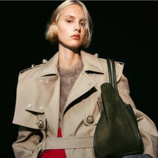 Blonde woman wearing trench coat and green bag