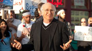 Larry David shrugs in front of some protesters.